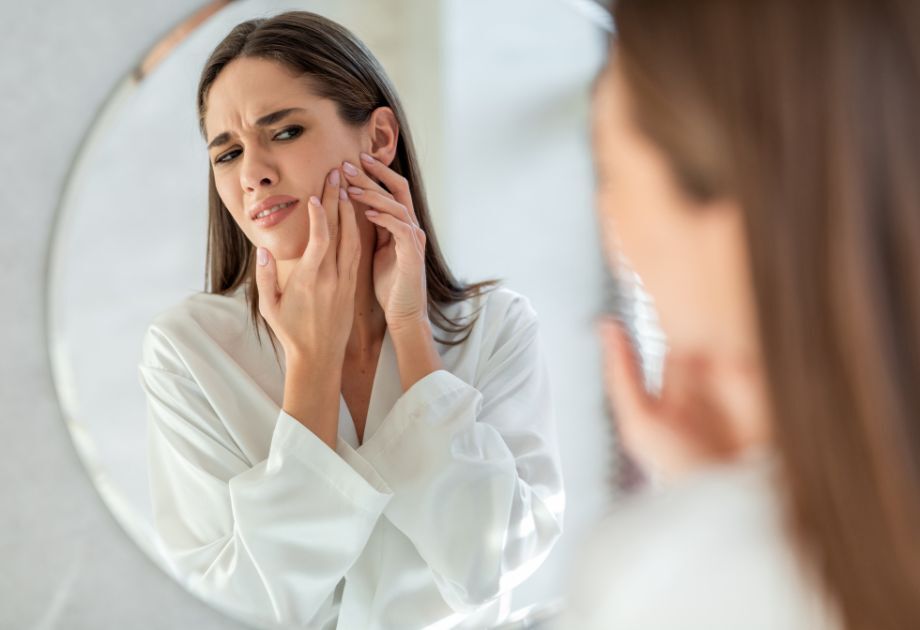 woman looking at skin in mirror